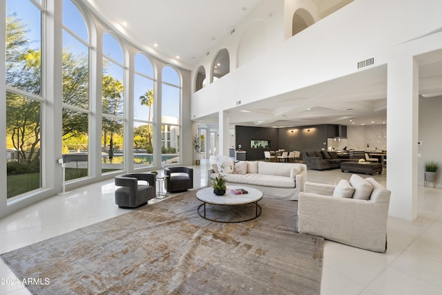 tiled living area with a high ceiling, visible vents, and recessed lighting