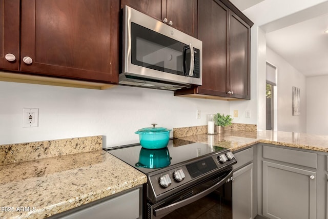 43142 N Outer Bank Dr, Anthem, AZ 85086 - kitchen with stainless steel microwave, light stone countertops, dark brown cabinets, and electric stove