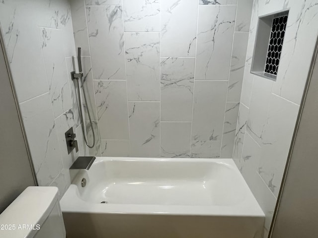 bathroom with tiled shower / bath combo and toilet