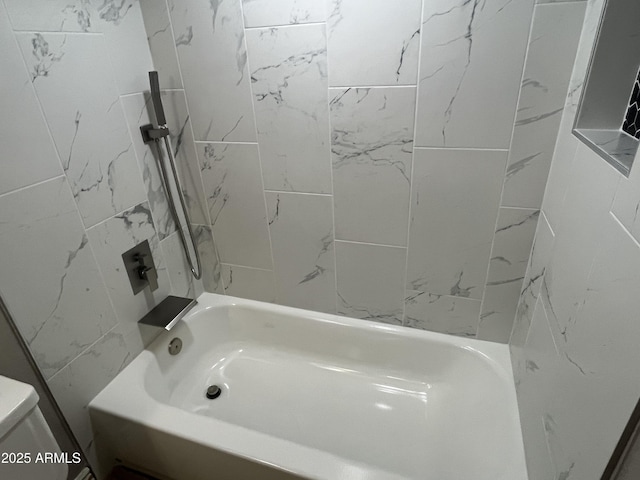 bathroom with toilet and tiled shower / bath