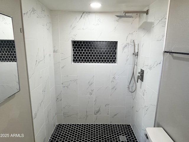 bathroom with a tile shower and toilet