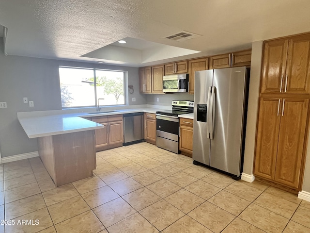 kitchen featuring a raised ceiling, sink, a textured ceiling, kitchen peninsula, and stainless steel appliances