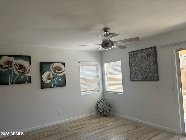 spare room featuring ceiling fan, light hardwood / wood-style floors, and a healthy amount of sunlight