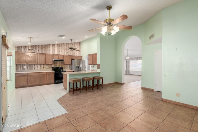 3140 N 114th Dr, Avondale, AZ 85392 - kitchen featuring stainless steel fridge, a peninsula, under cabinet range hood, ceiling fan with notable chandelier, and electric range