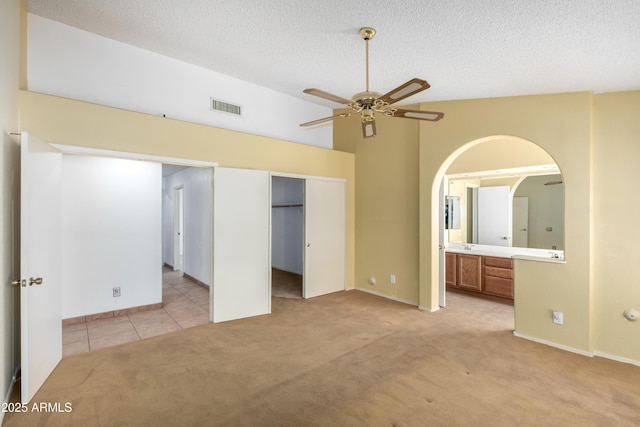 3140 N 114th Dr, Avondale, AZ 85392 - unfurnished bedroom with visible vents, a textured ceiling, connected bathroom, light tile patterned flooring, and light carpet