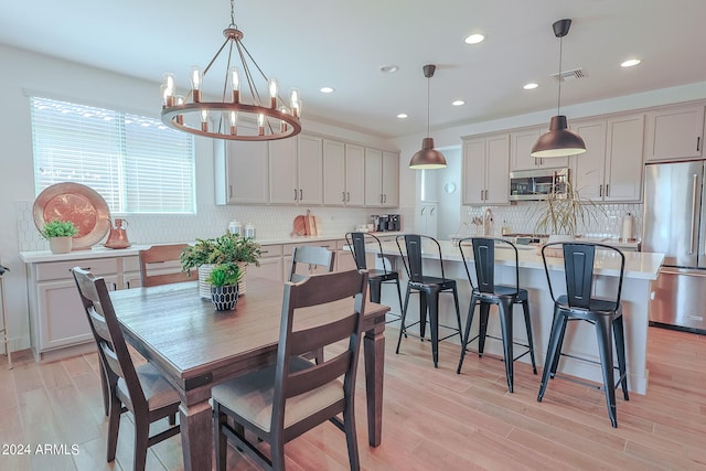 dining room with light wood-type flooring and an inviting chandelier