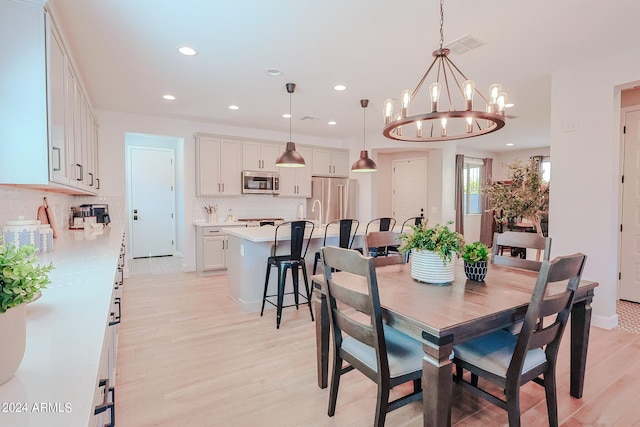 dining space with light hardwood / wood-style floors, sink, and a notable chandelier