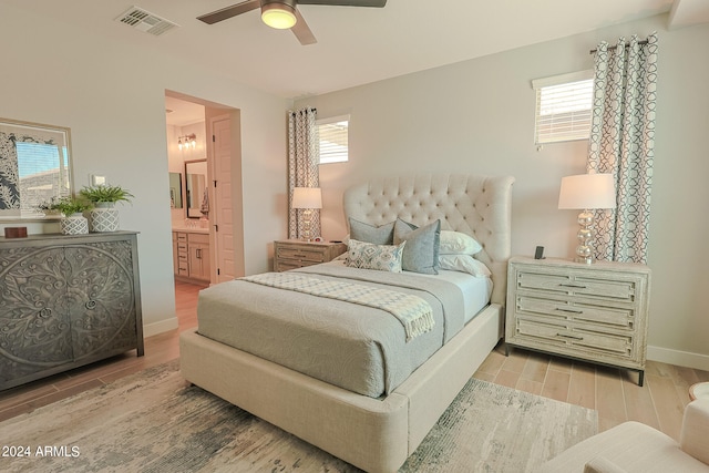 bedroom with ceiling fan, light wood-type flooring, ensuite bathroom, and multiple windows