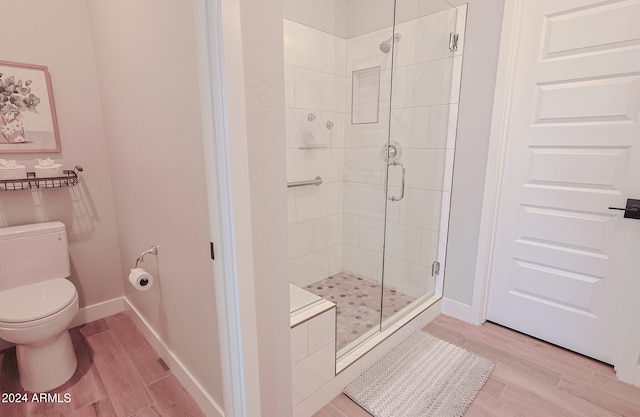 bathroom featuring walk in shower, hardwood / wood-style floors, and toilet