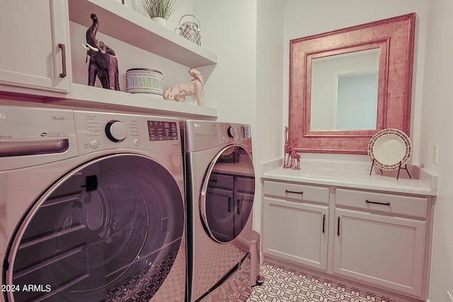 clothes washing area with cabinets and washing machine and dryer