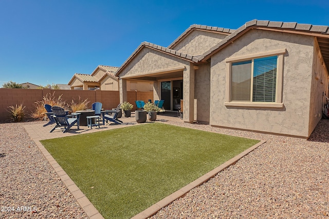 rear view of property with a lawn, a patio, and an outdoor fire pit