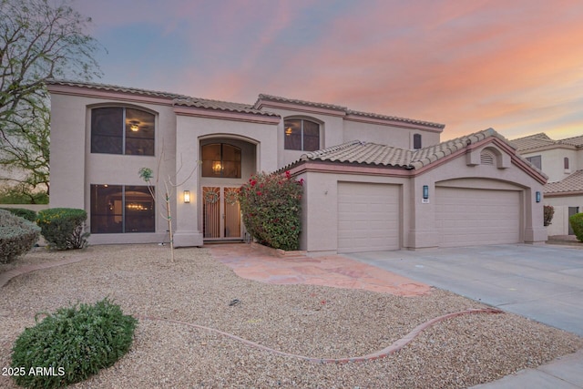 mediterranean / spanish-style house featuring driveway, an attached garage, a tile roof, and stucco siding