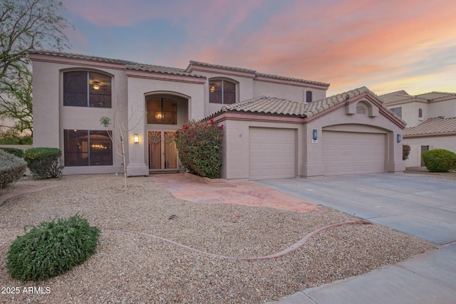 mediterranean / spanish home featuring a garage, driveway, a tile roof, and stucco siding