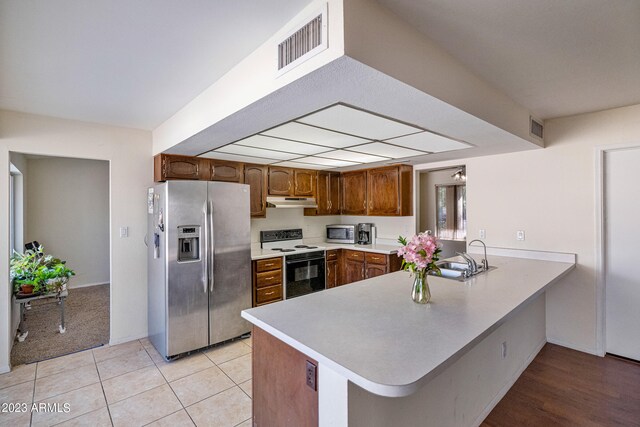 kitchen with light tile flooring, stainless steel appliances, kitchen peninsula, and sink