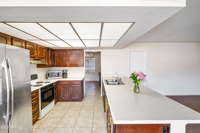 kitchen with appliances with stainless steel finishes, sink, a kitchen island with sink, and light tile floors