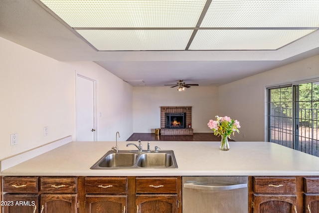 kitchen featuring a fireplace, stainless steel dishwasher, sink, and ceiling fan