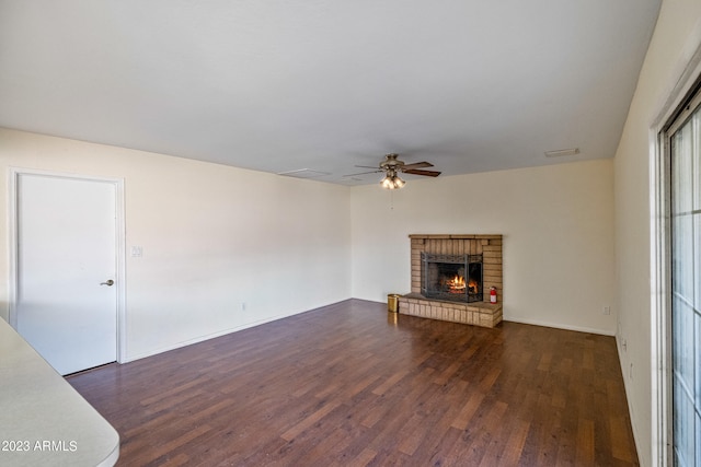 unfurnished living room featuring dark hardwood / wood-style floors, ceiling fan, and a brick fireplace