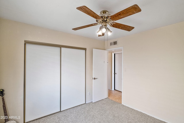 unfurnished bedroom featuring ceiling fan, light carpet, and a closet