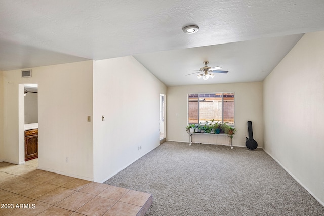 empty room featuring light tile floors, a textured ceiling, and ceiling fan