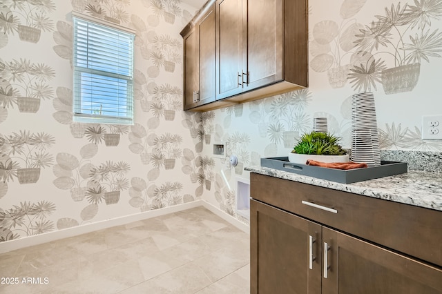 clothes washing area featuring light tile patterned flooring, hookup for an electric dryer, baseboards, cabinet space, and wallpapered walls