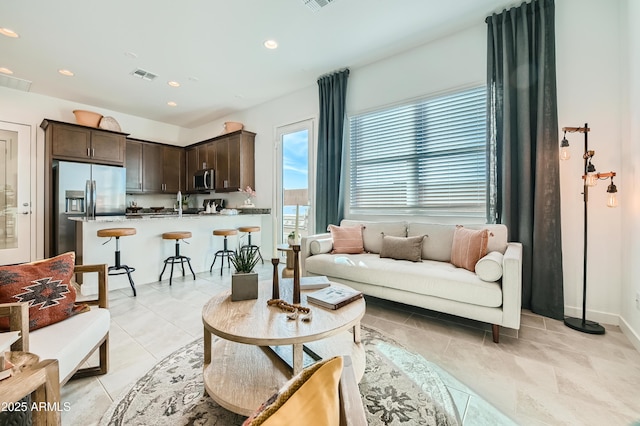 living area featuring light tile patterned floors, baseboards, visible vents, and recessed lighting