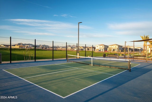 view of tennis court featuring fence and a residential view