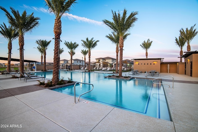 pool with a patio, fence, and a residential view