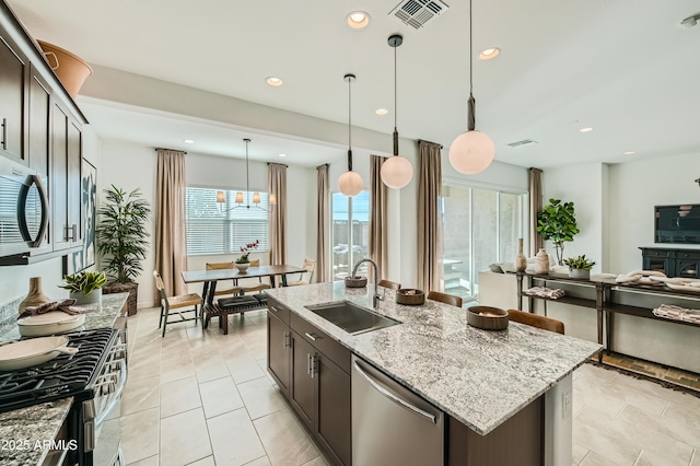 kitchen featuring a center island with sink, visible vents, open floor plan, stainless steel appliances, and a sink