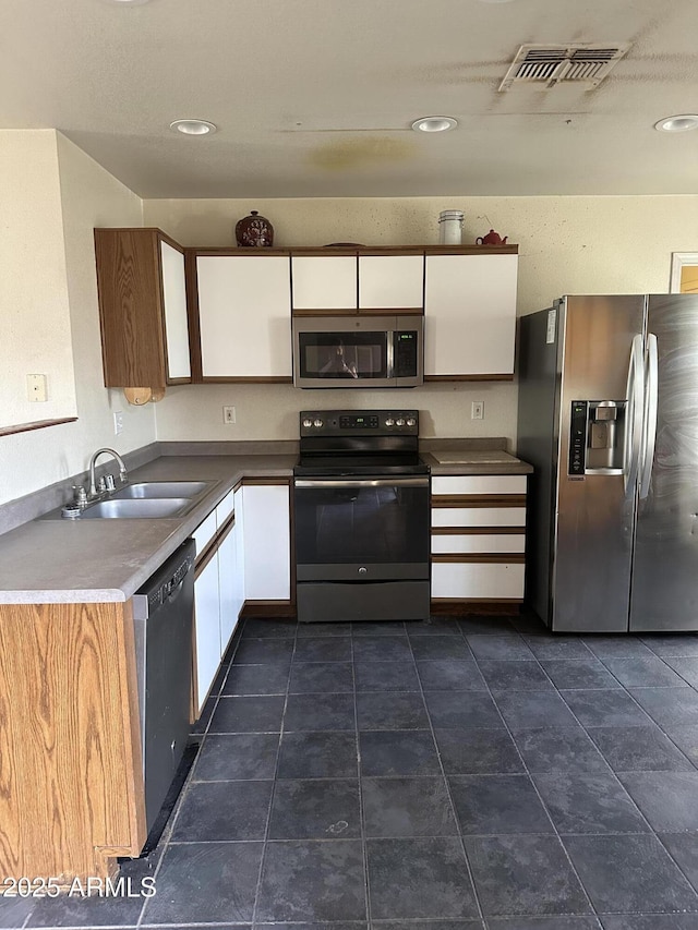 kitchen with stainless steel appliances, a sink, visible vents, and white cabinetry