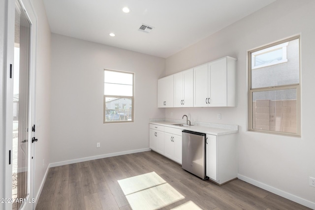 kitchen with a wealth of natural light, white cabinetry, dishwasher, and light hardwood / wood-style floors