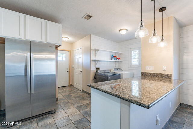 kitchen featuring separate washer and dryer, decorative light fixtures, white cabinetry, stainless steel fridge, and kitchen peninsula