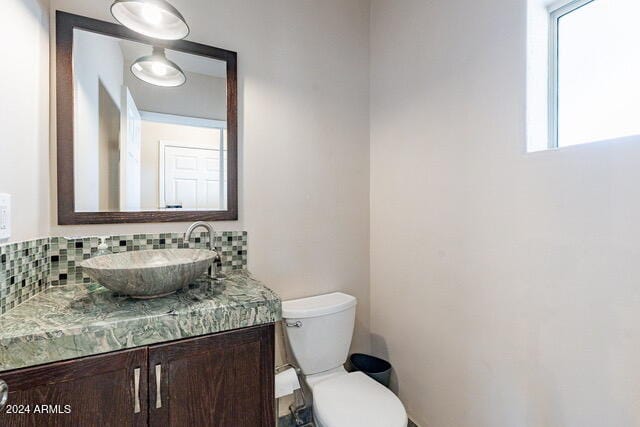 bathroom with plenty of natural light, toilet, vanity, and tasteful backsplash