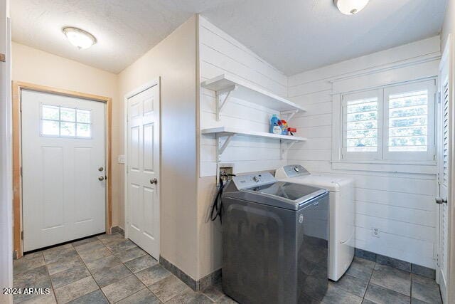 clothes washing area featuring washer and clothes dryer and wood walls