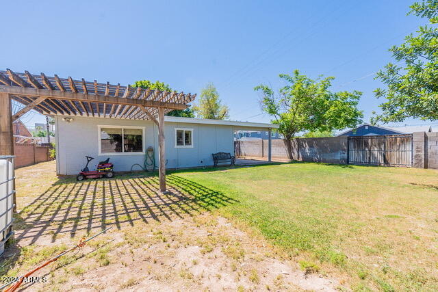 rear view of property featuring a lawn and a pergola