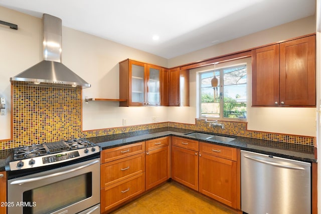 kitchen with dark stone countertops, decorative backsplash, sink, stainless steel appliances, and wall chimney exhaust hood