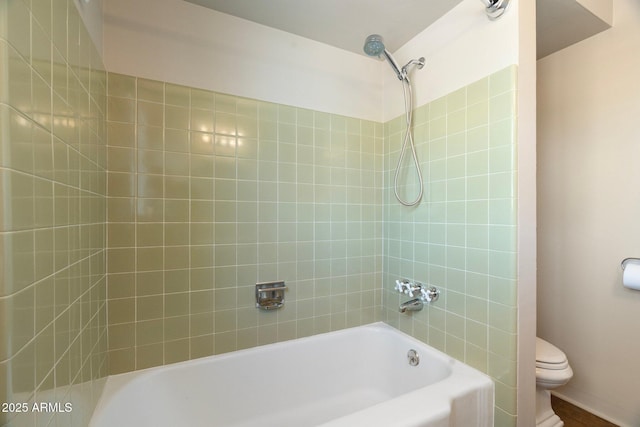 bathroom with toilet and tiled shower / bath combo