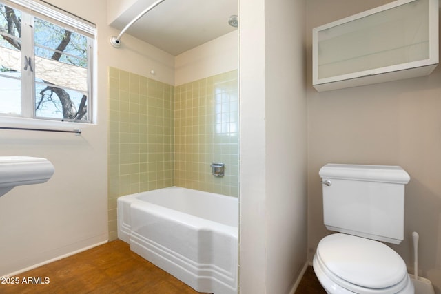 bathroom with toilet, tiled shower / bath, and hardwood / wood-style flooring