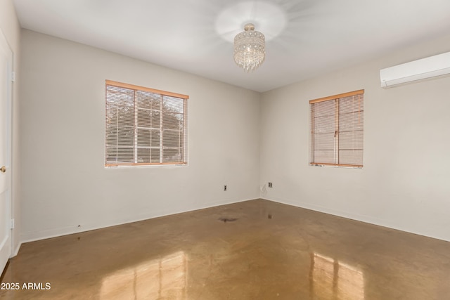 empty room with a notable chandelier, a wall mounted AC, and concrete flooring