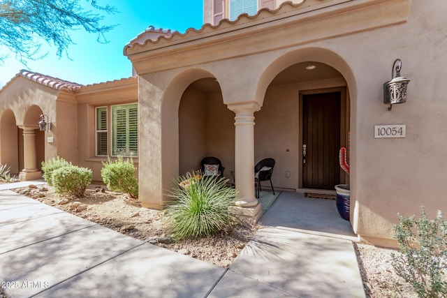 entrance to property featuring a tiled roof and stucco siding