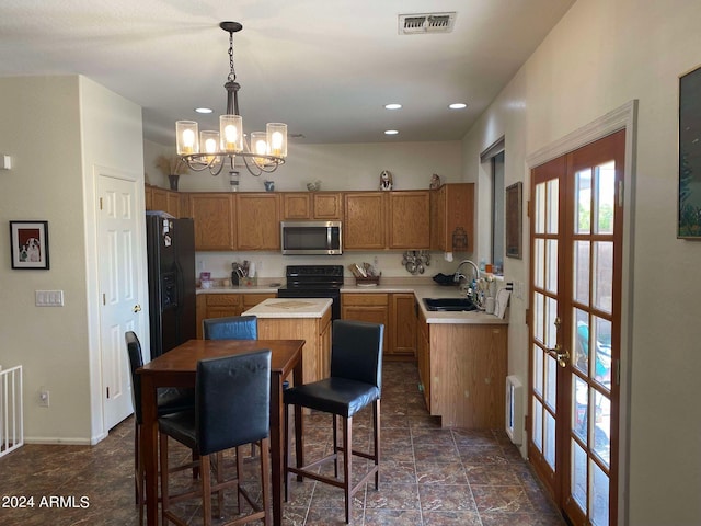 kitchen featuring a kitchen island, a chandelier, black appliances, sink, and decorative light fixtures