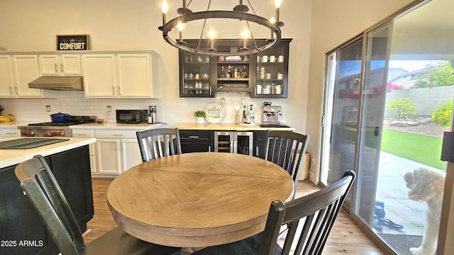 3002 W Caravaggio Ln, Phoenix, AZ 85086 - kitchen with under cabinet range hood, light wood-style flooring, range, a chandelier, and light countertops