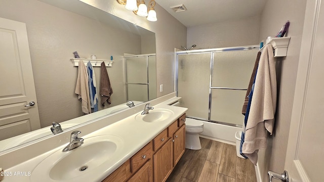 3002 W Caravaggio Ln, Phoenix, AZ 85086 - bathroom featuring wood finished floors, double vanity, combined bath / shower with glass door, and toilet