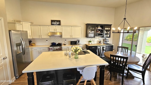 3002 W Caravaggio Ln, Phoenix, AZ 85086 - kitchen with appliances with stainless steel finishes, under cabinet range hood, light countertops, a chandelier, and white cabinetry