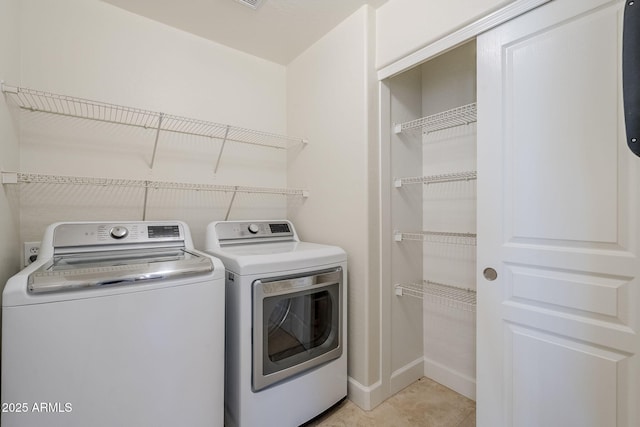 clothes washing area with washing machine and clothes dryer and light tile patterned floors