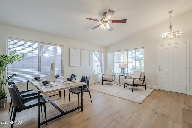 dining room featuring light hardwood / wood-style floors, vaulted ceiling, and ceiling fan with notable chandelier