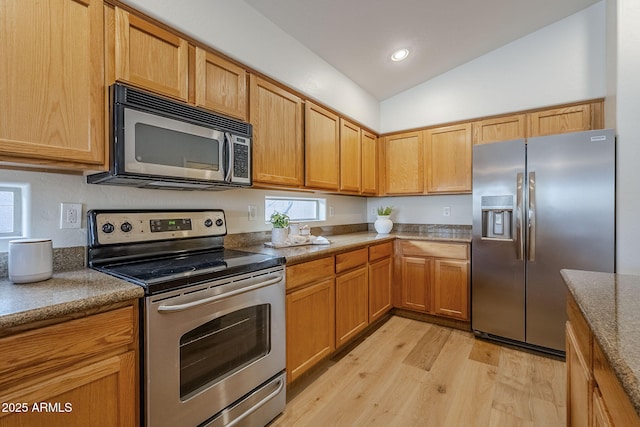 kitchen featuring appliances with stainless steel finishes, light wood-type flooring, and vaulted ceiling