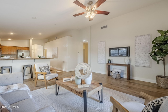 living room featuring vaulted ceiling, light wood-type flooring, and ceiling fan