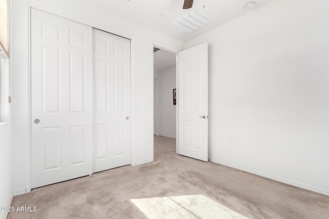 unfurnished bedroom with ceiling fan, light carpet, and a closet