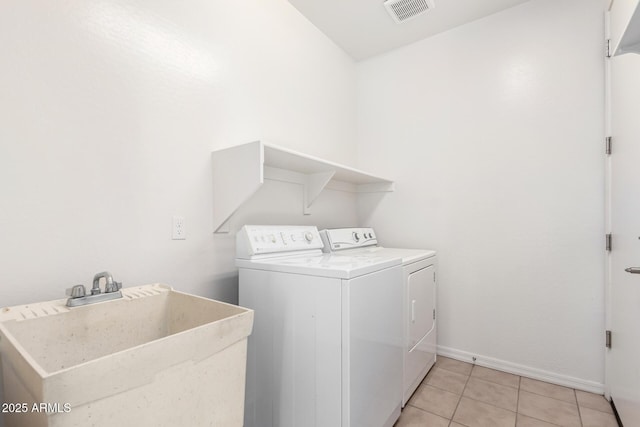 laundry area featuring sink, washing machine and dryer, and light tile patterned floors