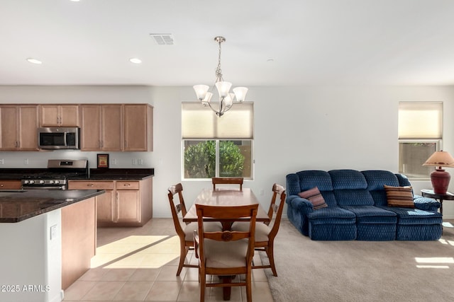 kitchen with stainless steel appliances, a notable chandelier, light tile patterned flooring, decorative light fixtures, and dark stone counters